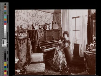 Anita Chartres sitzt an einem Pianola, ca. 1898